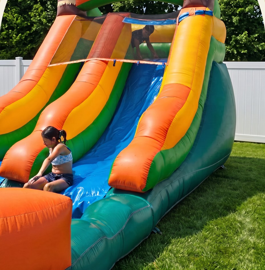 Children enjoying a tropical inflatable water slide at a backyard party